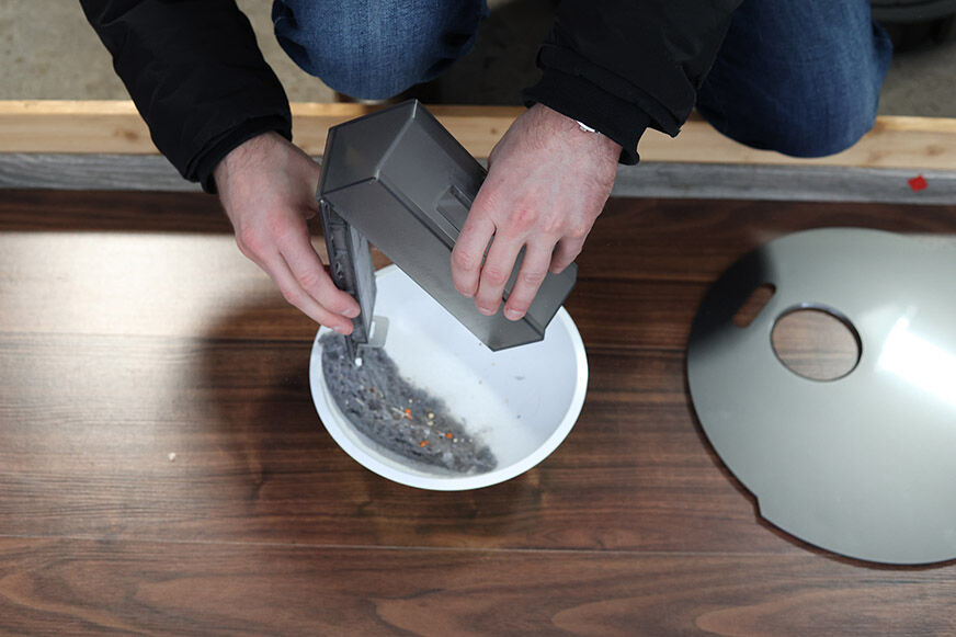 Der Straubbehälter des Dreame L10s Pro wird per Hand ausgeleert.